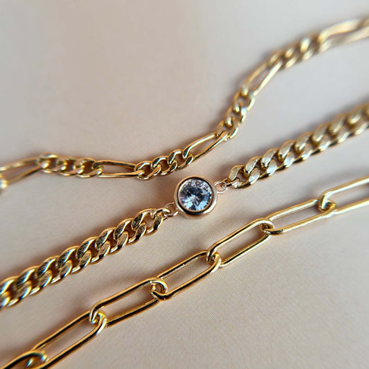 Flat lay of a gold vermeil bezel-set CZ charm paired with two other chains, styled to reflect Weld’s bespoke stacking service—where clients mix and match for a look that’s effortlessly their own.
