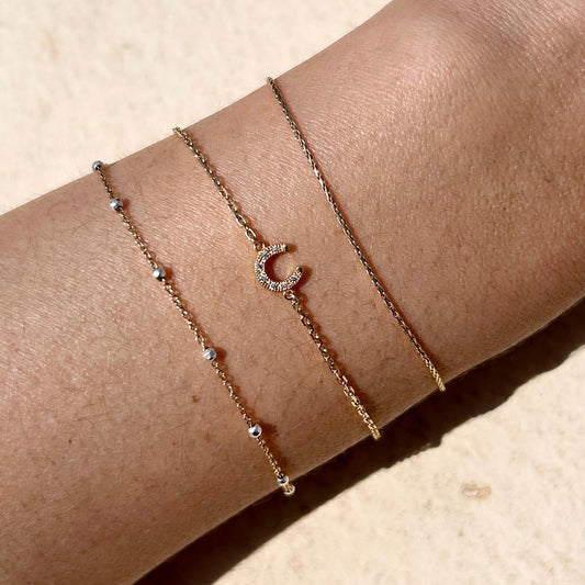 Gold vermeil pavé horseshoe charm bracelet glinting in the sunshine on a wrist – a meaningful permanent jewellery gift designed for luck, love, and lasting wear.