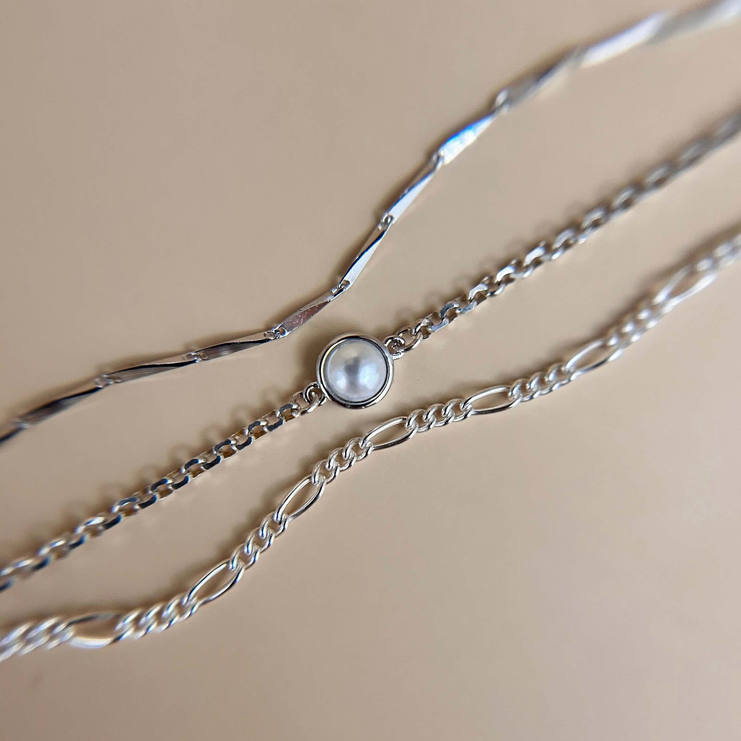Flat lay of a sterling silver charm featuring a smooth synthetic pearl, styled on a neutral background to highlight its elegant and minimal design.