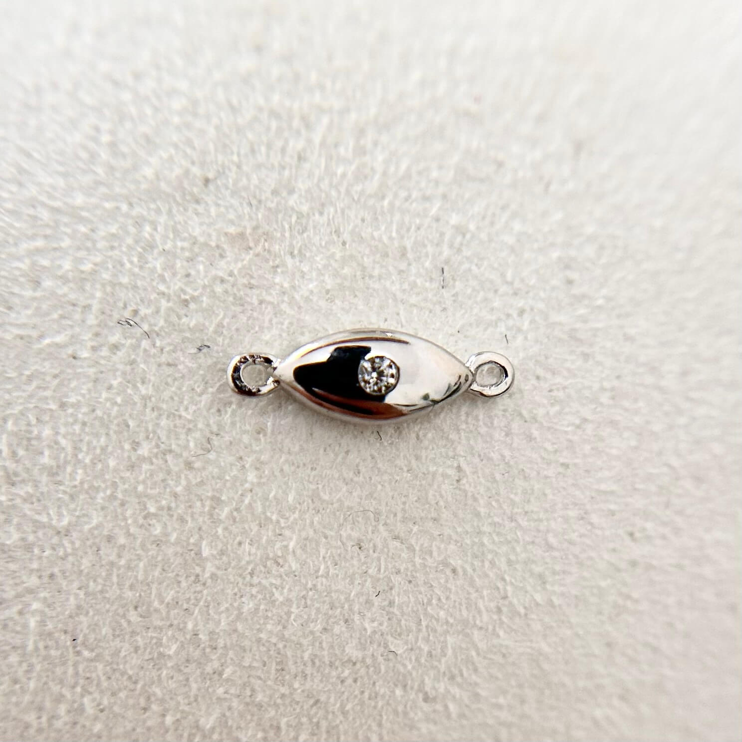 Sterling silver evil eye charm with cubic zirconia, a symbol of protection.