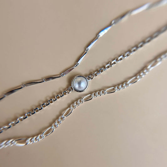 Flat lay of a sterling silver charm featuring a smooth synthetic pearl, styled on a neutral background to highlight its elegant and minimal design.
